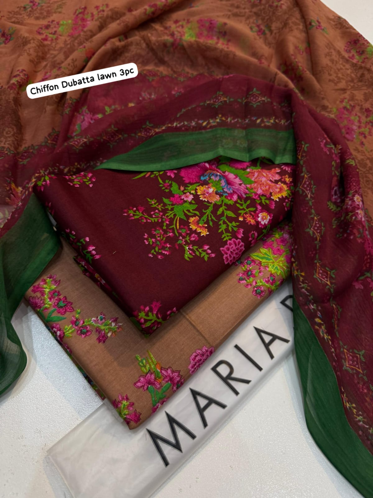 Folded fabric with floral patterns in a box labeled 'Maria'.