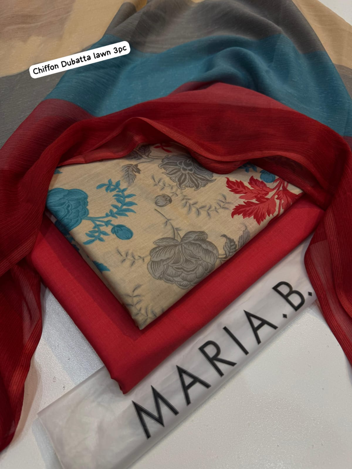 Fabric swatch with floral pattern on a red background, with 'Maria B.' branding.