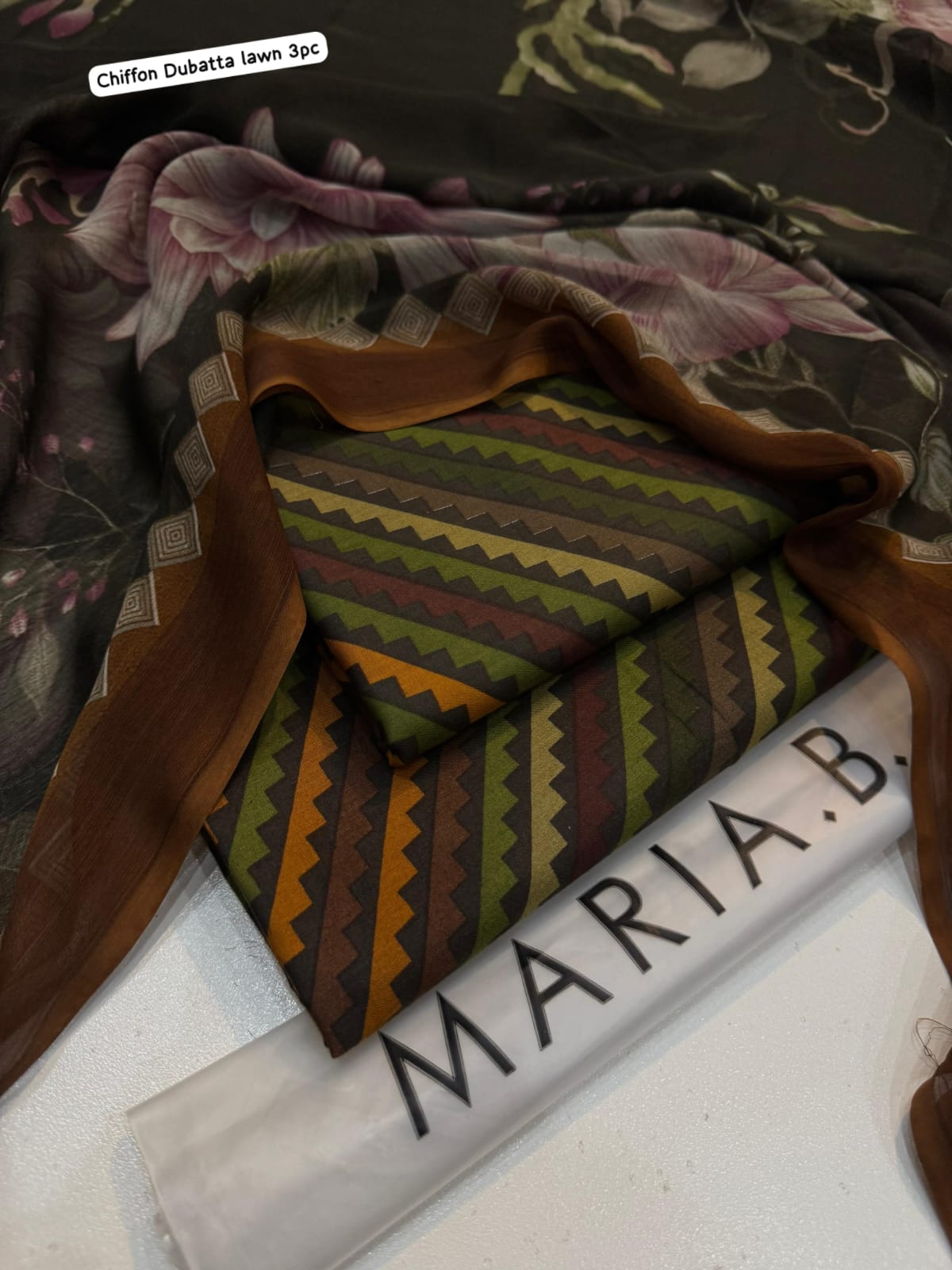 Stack of fabric with a patterned piece on top, labeled 'Maria B.'