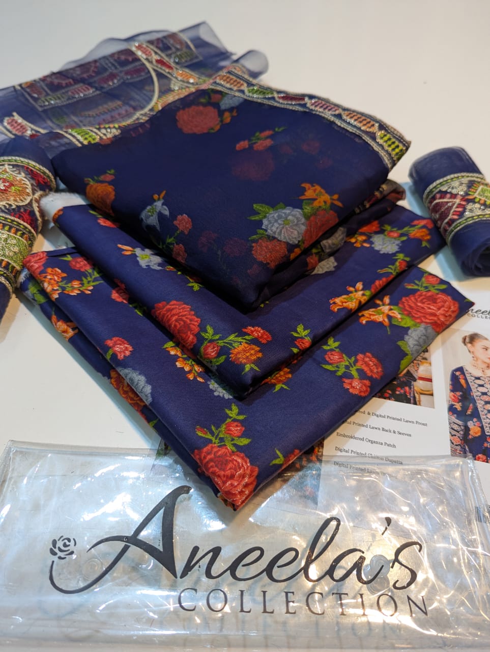 Navy blue fabric with floral patterns on a white surface, branded 'Aneela's Collection'.