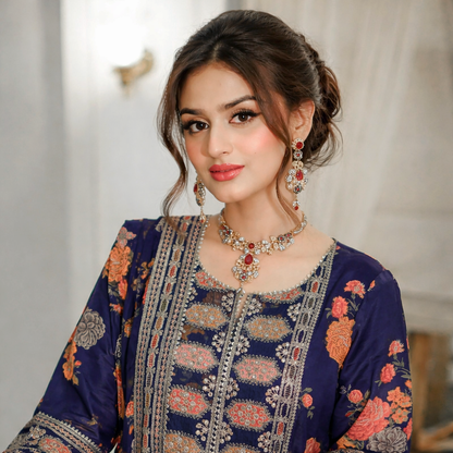 Woman wearing a traditional embroidered outfit with jewelry against a neutral background