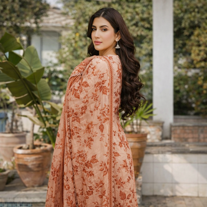 Woman in a floral dress standing outdoors with plants and a building in the background