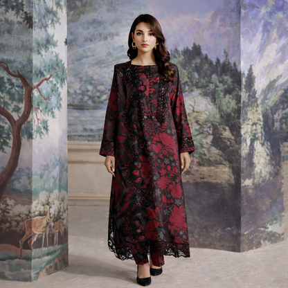 Woman wearing a black and red floral dress standing in front of a decorative wall.