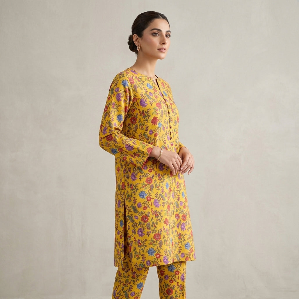 Woman wearing a yellow floral kurta with pants against a plain background