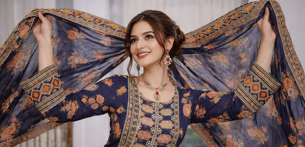 Woman in traditional embroidered outfit with a floral shawl, indoor setting