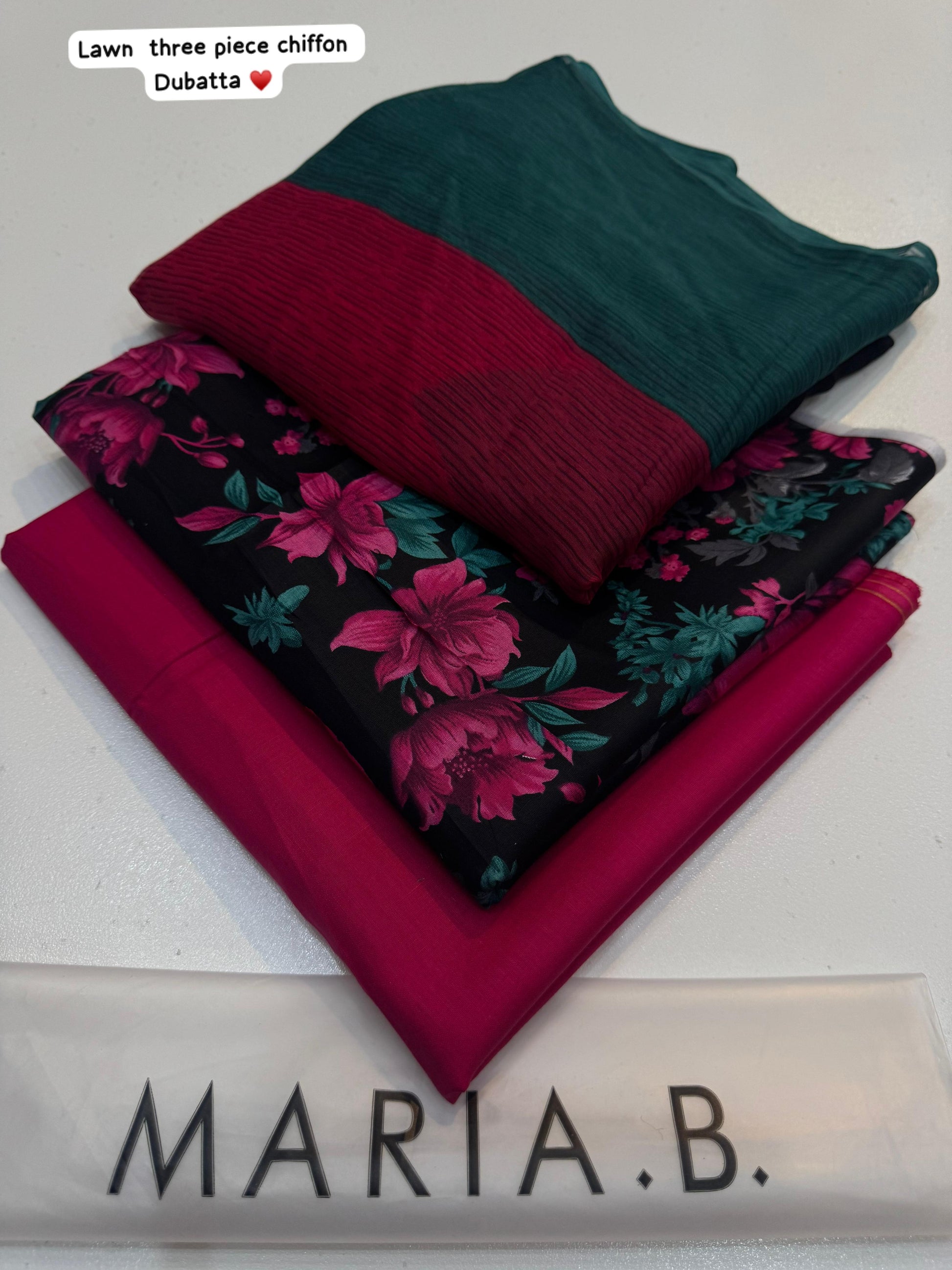 Stack of fabric pieces in green, red, and floral pattern with 'Maria B.' branding.