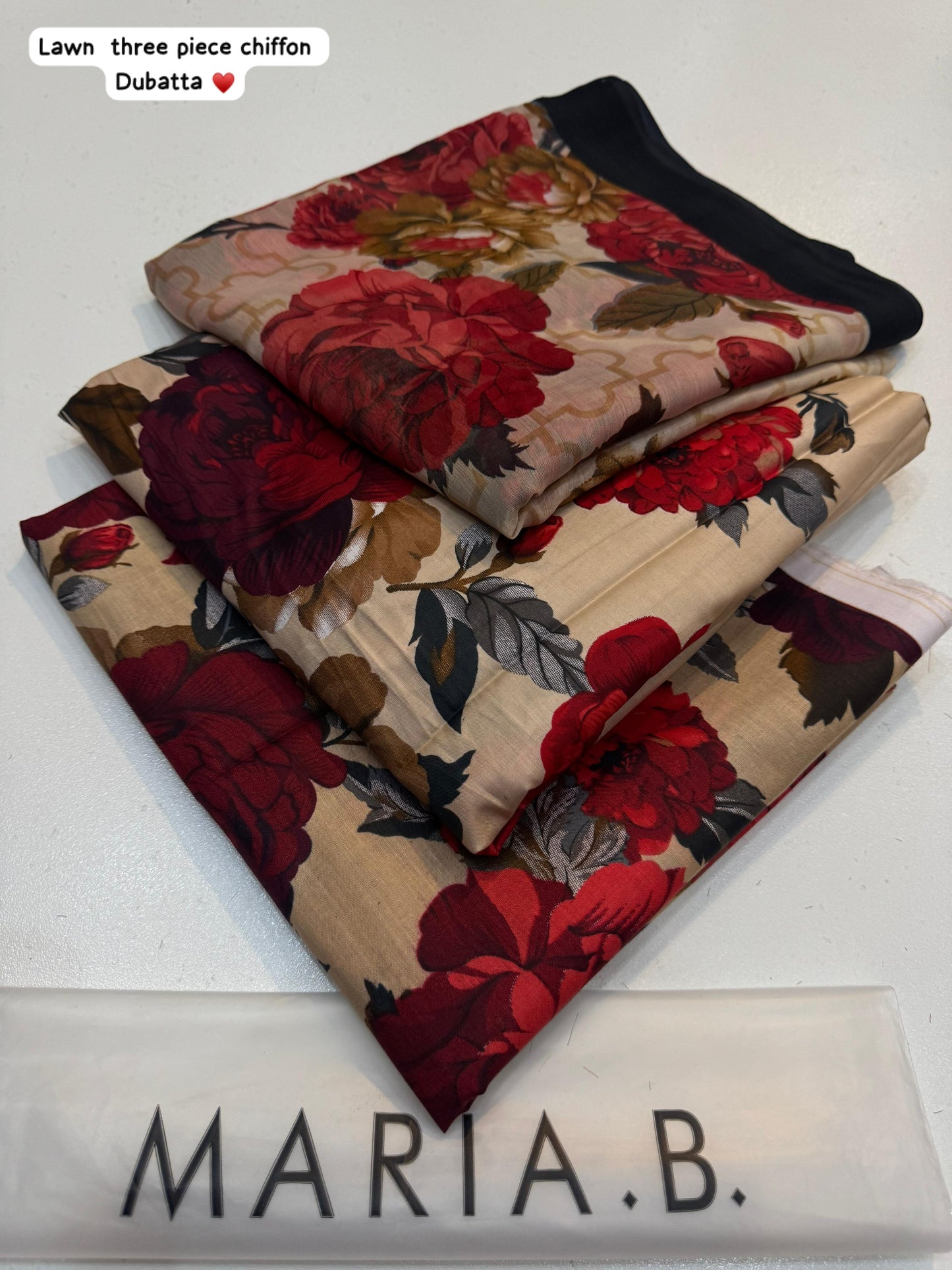 Stack of floral fabric pieces with 'Maria B.' branding on a white background