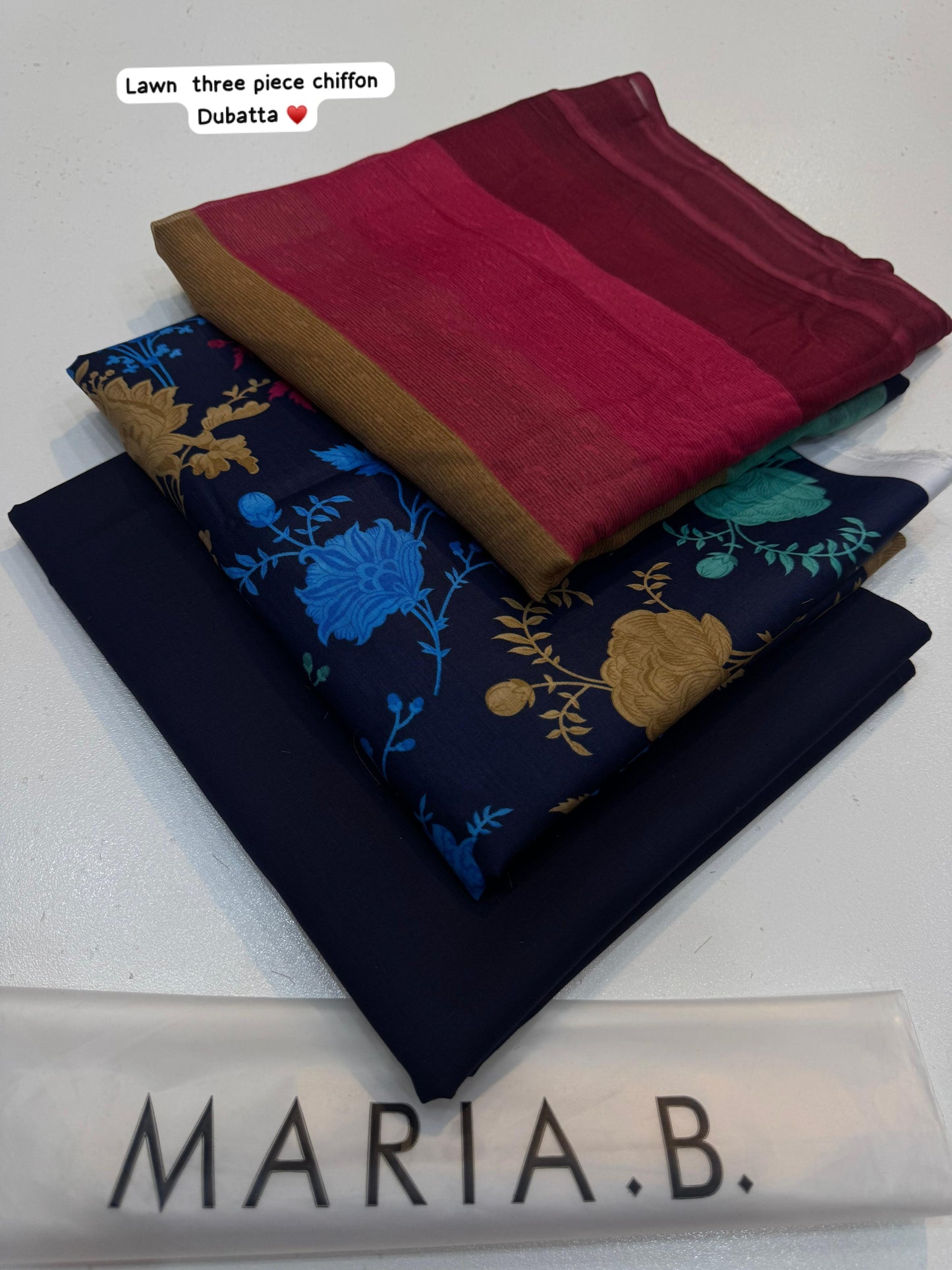 Three pieces of fabric in red, blue, and black with floral patterns on a white background, branded 'Maria B'.